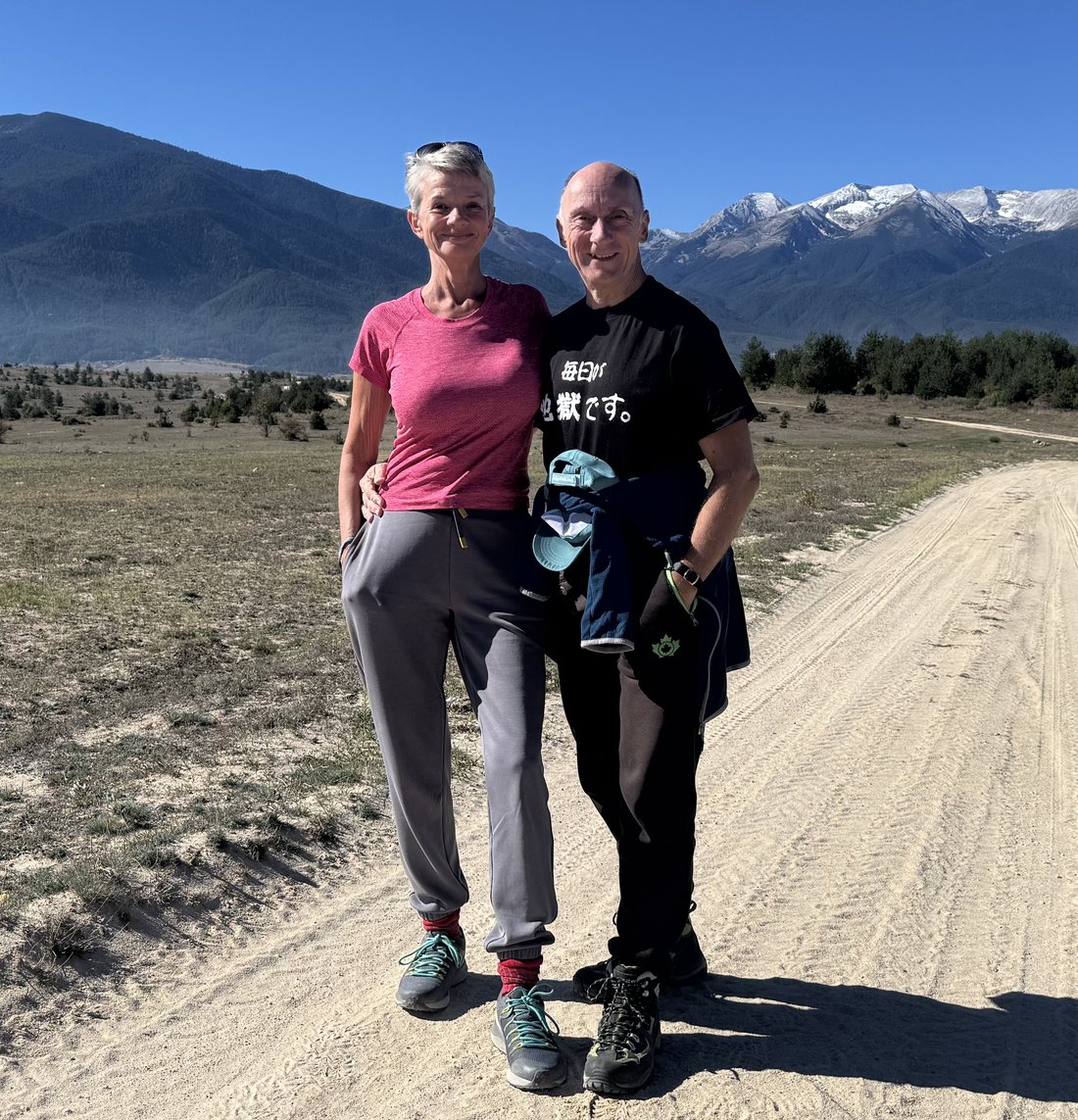 Andrea and Ralf on a country track in front of the snow-capped peaks of the Pirin mountains
