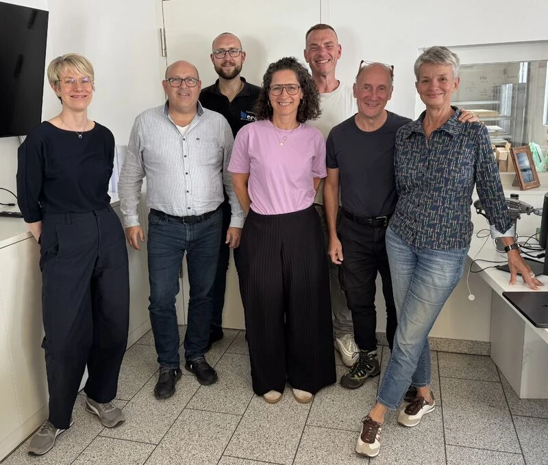 Gruppenfoto von sieben Personen im Büro der Tischlerei Berg, aufgenommen während der Walz